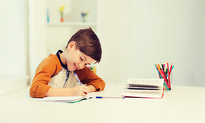 Image showing smiling student boy writing to notebook at home