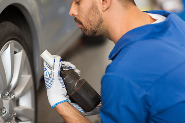 Image showing mechanic with screwdriver changing car tire