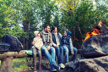 Image showing happy family sitting on bench at camp fire