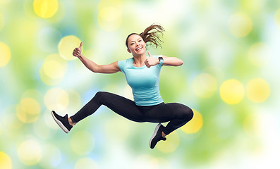 Image showing happy smiling sporty young woman jumping in air
