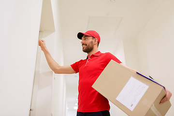 Image showing delivery man with parcel box knocking on door