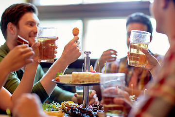 Image showing happy friends eating and drinking at bar or pub