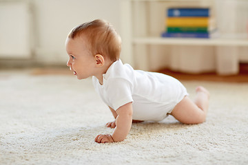 Image showing little baby in diaper crawling on floor at home