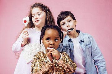 Image showing lifestyle people concept: diverse nation children playing together, caucasian boy with african little girl holding candy happy smiling 