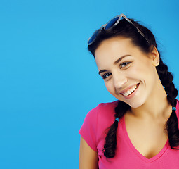 Image showing young pretty teenage modern hipster girl posing emotional happy smiling on blue background, lifestyle people concept 