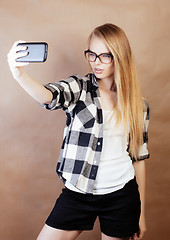 Image showing young pretty blond hipster girl making selfie on warm brown background, lifestyle people concept