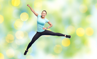 Image showing happy smiling sporty young woman jumping in air