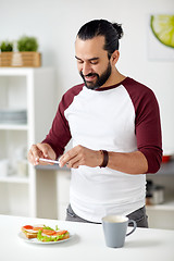 Image showing man photographing food by smartphone at home