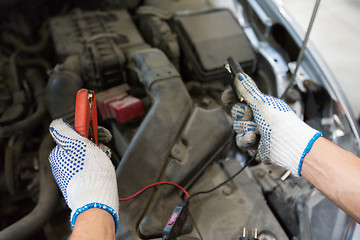 Image showing auto mechanic man with cleats charging battery