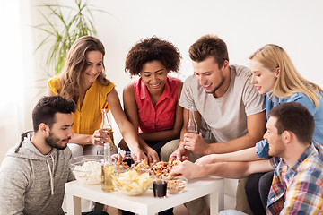 Image showing happy friends with drinks eating pizza at home