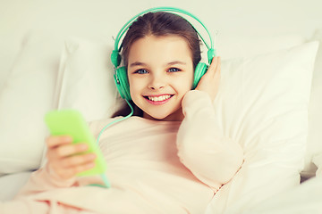 Image showing happy girl lying in bed with smartphone at home