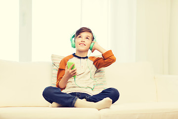 Image showing happy boy with smartphone and headphones at home