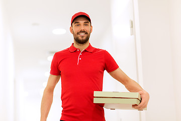 Image showing happy delivery man with pizza boxes in corridor