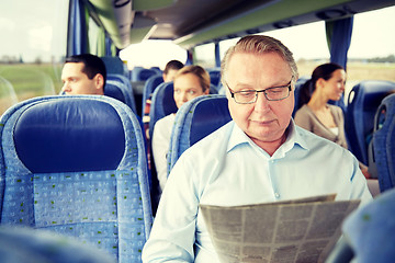 Image showing happy senior man reading newspaper in travel bus