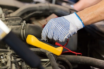 Image showing auto mechanic man with multimeter testing battery