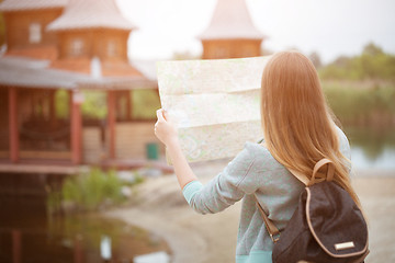 Image showing Back side of traveler girl searching right direction on map, orange sunset light, traveling along Europe