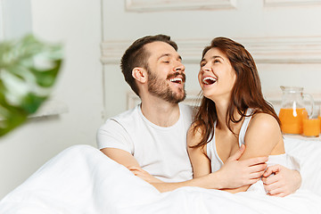 Image showing Young adult heterosexual couple lying on bed in bedroom