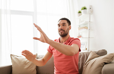 Image showing happy man touching something imaginary at home