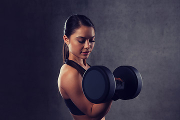 Image showing young woman flexing muscles with dumbbells in gym