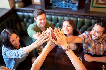 Image showing friends drinking beer and making high five at bar