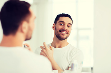 Image showing man with perfume looking to mirror at bathroom