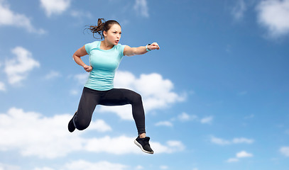 Image showing sporty woman jumping in fighting pose over sky