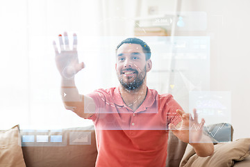 Image showing happy man touching virtual screen at home