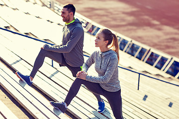 Image showing couple stretching leg on stands of stadium