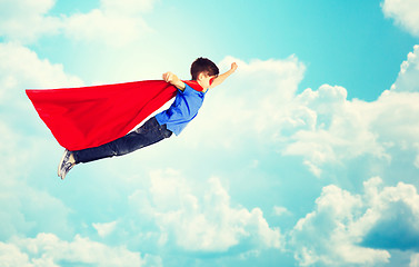 Image showing boy in red superhero cape and mask flying over sky