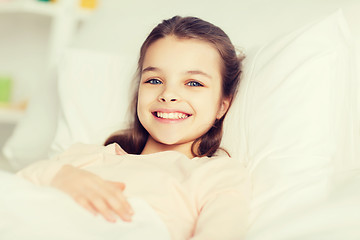 Image showing happy smiling girl lying awake in bed at home