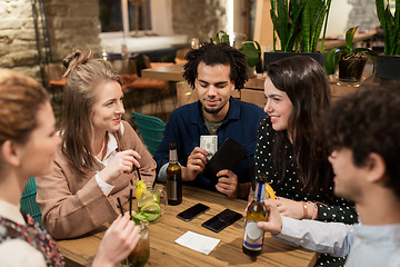 Image showing friends with drinks, money and bill at bar