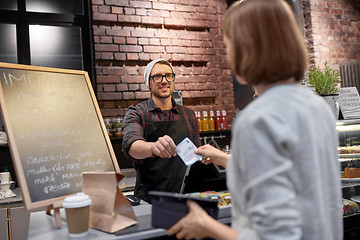 Image showing happy barman and woman paying money at cafe