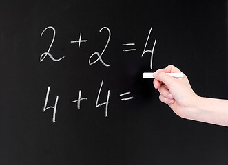 Image showing hand with chalk writing numbers on blackboard