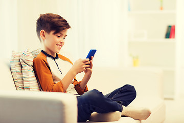 Image showing boy with smartphone texting or playing at home