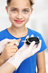 Image showing Girl with diabetes to measure blood sugar levels using a glucometer