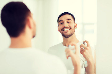Image showing man with perfume looking to mirror at bathroom