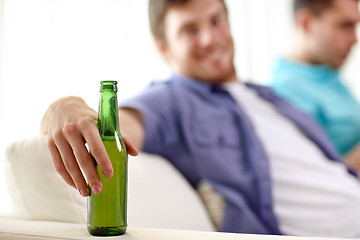 Image showing men with beer bottles sitting on sofa at home