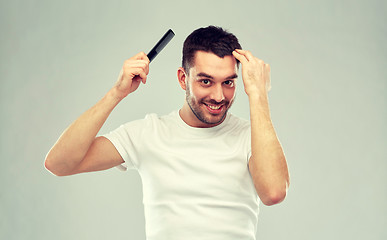 Image showing happy man brushing hair with comb over gray