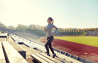 Image showing happy young woman running upstairs on stadium