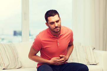 Image showing unhappy man suffering from stomach ache at home