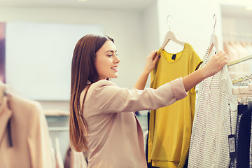 Image showing happy young woman choosing clothes in mall
