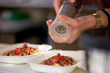 Image showing close up of cook hands spicing waffle