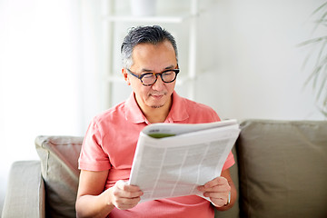 Image showing happy man in glasses reading newspaper at home