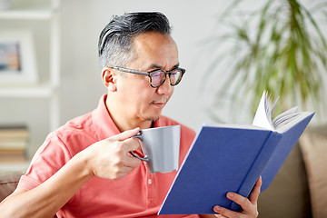 Image showing man sitting on sofa and reading book at home