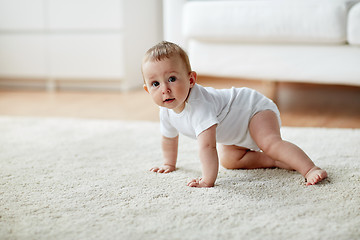 Image showing little baby in diaper crawling on floor at home