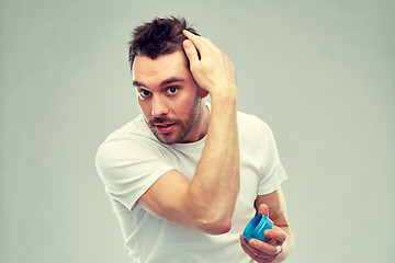 Image showing happy young man styling his hair with wax or gel