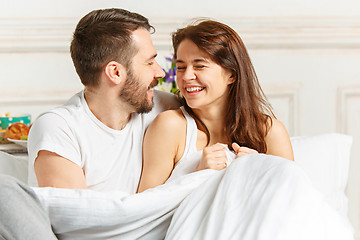 Image showing Young adult heterosexual couple lying on bed in bedroom