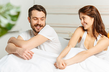 Image showing Young adult heterosexual couple lying on bed in bedroom