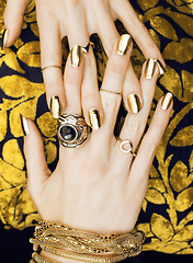 Image showing woman hands with golden manicure lot of jewelry on fancy dress close up