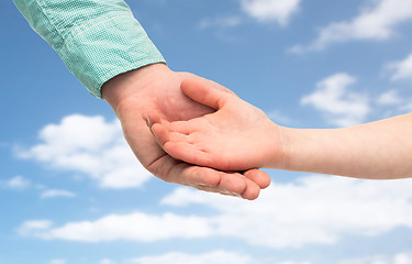 Image showing father and child holding hands over blue sky